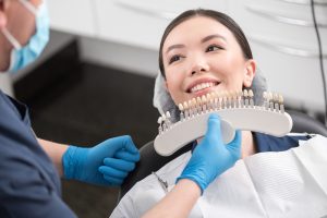 dentist matching patient's tooth color to sample prosthetics