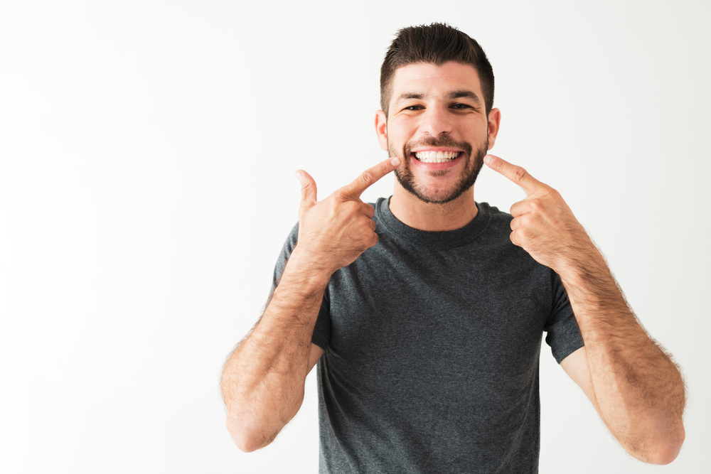 A man points to his smile which was corrected using smile makeovers.
