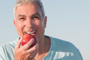a man eats an apple using the strength of his dental crowns